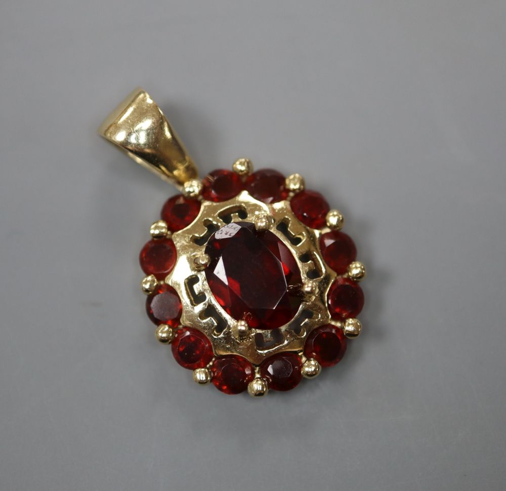 A modern 585 and garnet set oval cluster pendant, 16mm, gross 3.6 grams.